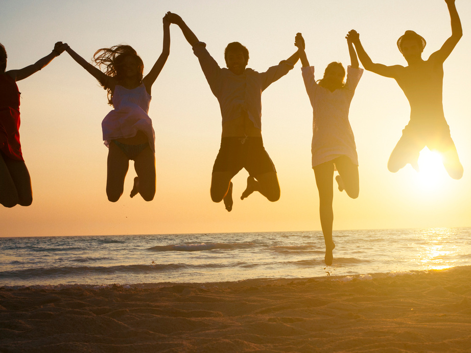 group of people jumping at beach. Backlight shot.